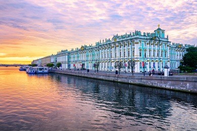 winter palace building housing hermitage museum reflects in neva river on dramatic sunrise, st petersburg, russia
