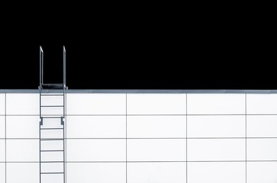 metal emergency stairs on white wall isolated on black background. minimalistic picture with plenty of copy space on the right