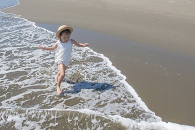 happy little girl playing at the beach