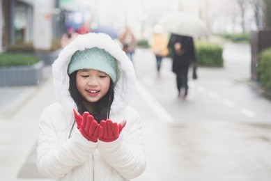 asian girl enjoying snow in a snowy day in the street of a town