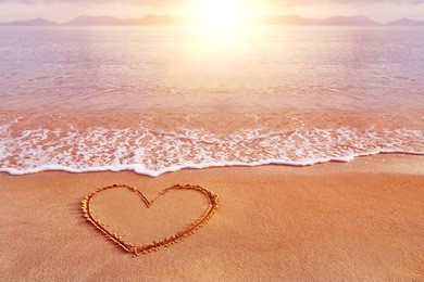 amazing sea sunrise view with a hand drawn heart as a symbol of love at golden sand.