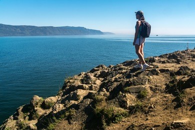 a girl stands on the edge of cape shamansky and admire lake baikal