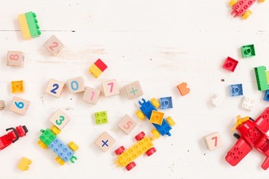 top view on wooden cubes with numbers and colorful toy bricks on a white wooden background. toys in the table