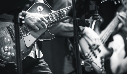 rock and roll music background, guitar players on a stage, monochrome photo with selective focus