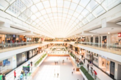blurred image interior of main hall shopping mall showing the ice rink and large skylight with natural light from glass roof. glazed barrel vault spanning central axis, fashion boutique along corridor