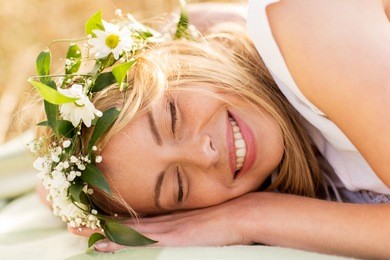 nature, summer holidays, vacation and people concept - happy smiling woman in wreath of flowers lying