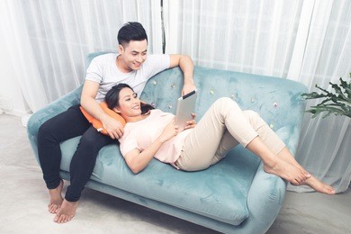 couple at home relaxing on sofa with digital tablet