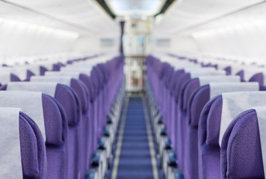 commercial aircraft cabin with rows of seats down the aisle,focus on front seat