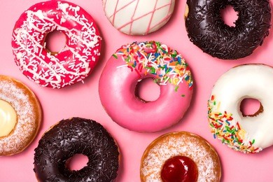 donuts with icing on pastel pink background. sweet donuts.