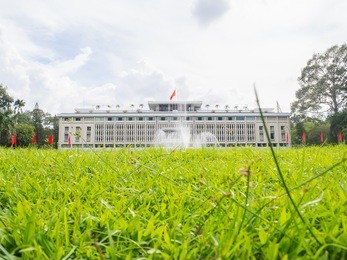 independence palace in ho chi minh city with grasses foreground, vietnam over cloudy day