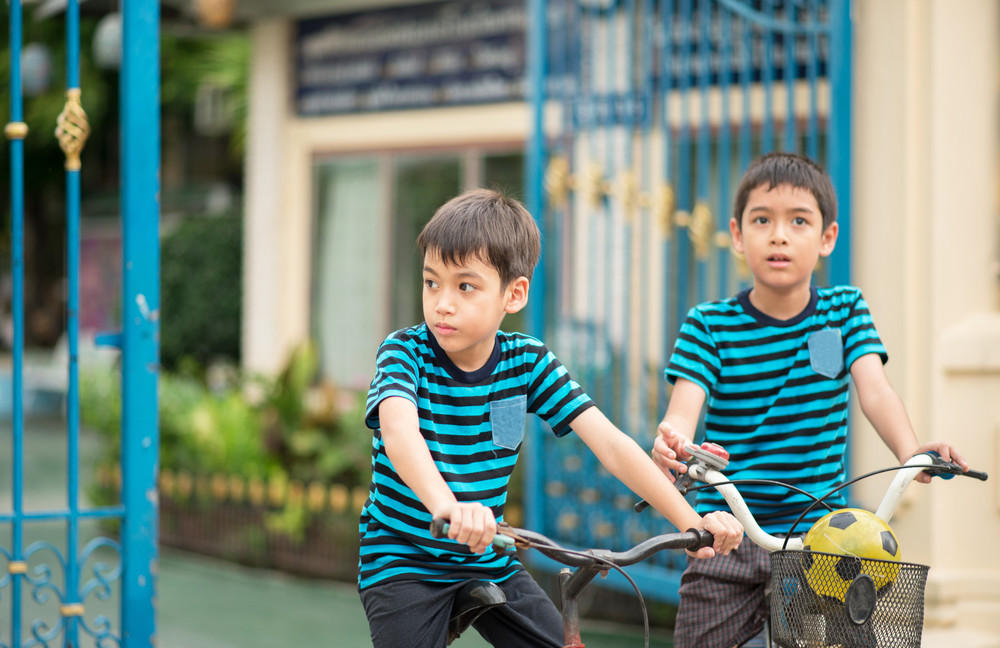 little boy riding bicycle on the road around the house 