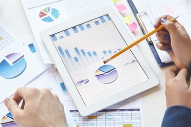team of marketing experts analyzing financial data to work out company's new strategy. coworkers sitting at table with touch pad and notes, developing business plan, discussing report, making remarks