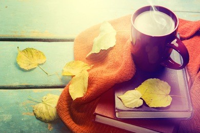hot tea and book with autumn leaves on wood background - seasonal relax concept.