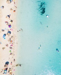 aerial view of sandy beach with tourists swimming in beautiful clear sea water