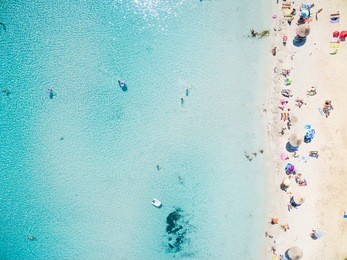 aerial view of sandy beach with tourists swimming in beautiful clear sea water