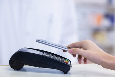woman paying bill through smartphone using nfc technology in pharmacy