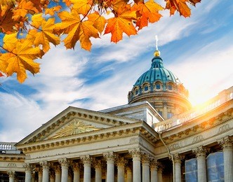 st petersburg, russia - kazan cathedral framed by maple leaves in at the autumn sunset. soft focus applied