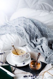 tray with honey and a cup of hot tea in the bed, lazy morning, warm winter mood