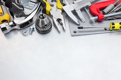 set of hand tools including hammer, clamp, screwdrivers and other on scratched metal surface background