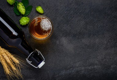 bottle and glass beer with wheat and hops as brewing ingredients in top view and copy space area