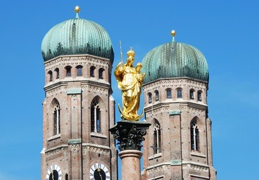 the golden sculpture of saint mary with the church of our lady (frauenkirche) in the background. view from the marienplatz in munich (germany, bavaria)