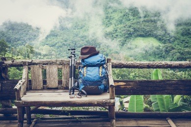 travel backpack on the wooden bench with landscape view of mountain and fog