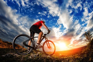 low angle view of cyclist standing with mountain bike on trail at sunset