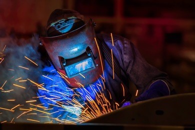 worker welding automotive part in car factory
