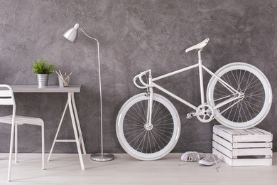 shot of a minimalistic workspace and a white vintage bicycle in a modern living room with grey walls