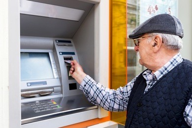 elderly man inserting credit card to atm