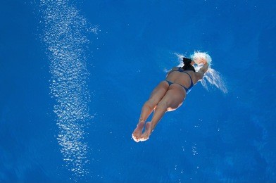 woman diver in the moment of touching water surface. lots of copy space, rotatable.