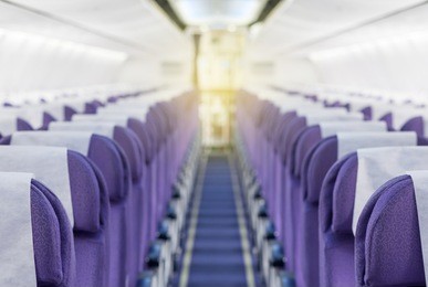 commercial aircraft cabin with rows of empty seats down the aisle