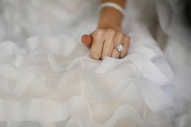 bride hand with beautiful diamond ring on white dress