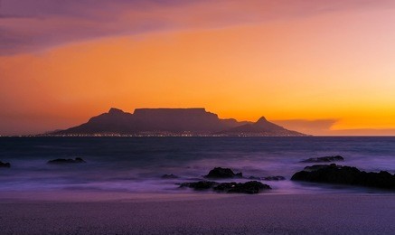 table mountain in cape town, south africa at sunset from bloubergstrand beach