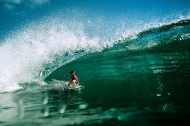 surfing girl riding a giant ocean wave. blue ocean water crashing with splashes and drops. water sport activity 