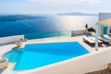 view of caldera and swimming pool in foreground, typical white architecture of imerovigli village on santorini island, greece