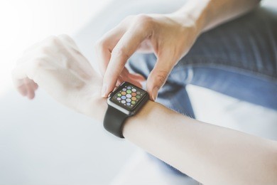 closeup of smart watch on female hand.girl dressed in blue jeans,sitting and using digital gadget.young woman presses a finger on the side button smartwatch.student using smart watch,checks messages.