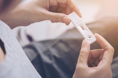 close up of woman hand holding a positive home pregnancy test.