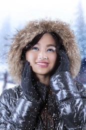 beautiful teenage girl wearing winter jacket while standing on the street in snowy day