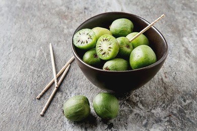new zealand exotic food. berry nergi, or small kiwi. in a brown plate. grey stone background