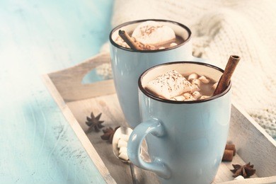 blue cup of hot chocolate drink with marshmallows and cinnamon on blue wooden background. winter time. holiday concept, selective focus, toned