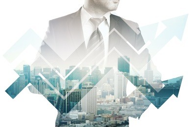 businessman in suit and abstract business chart arrows on city background. double exposure. financial growth concept
