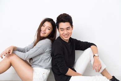 young asian couple sitting back to back