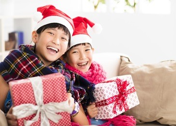 happy little girls showing christmas gift on  sofa