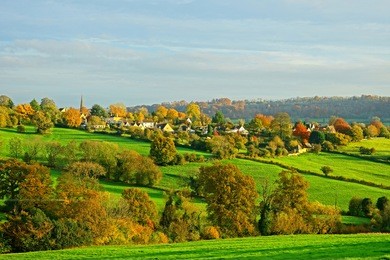 a picturesque panorama view of the village of painswick bathed in late afternoon sunshine in the heart of the cotswolds, gloucestershire, england, uk