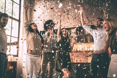 confetti fun. group of happy young people throwing confetti and jumping while enjoying home party on the kitchen 