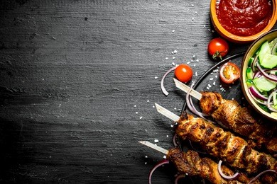 shish kebab of pork and salad. on the black wooden table.