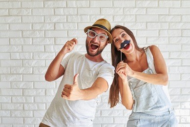  funny couple holding paper moustache and glasses, they are laughing