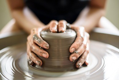 woman potter hands makes on the pottery wheel clay pot