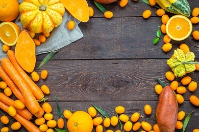 autumn nature concept, orange vegetables and fruits on dark wooden background with free space for text, thanksgiving dinner, top view